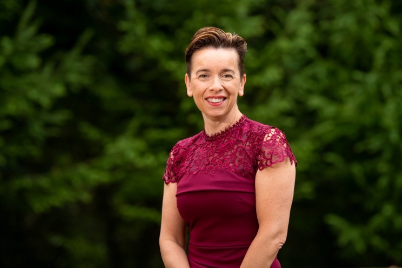 woman standing and smiling, posing for a photo